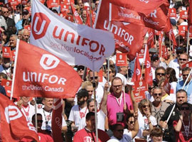Large crowd of Unifor members standing outside holding flags
