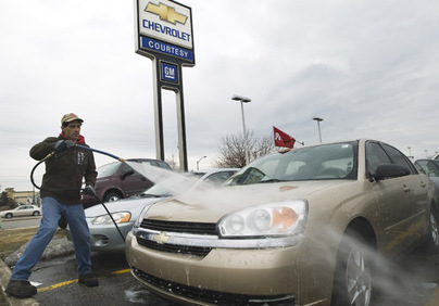 An employee at a GM dealership washes cars in Toronto, March 5, 2009.