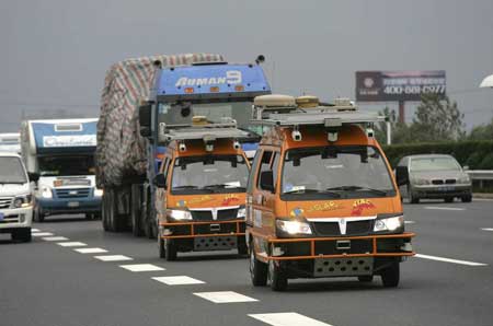 Two bright orange driverless vehicles, equipped with laser scanners and cameras to detect and help avoid obstacles, travel on the highway Tuesday in Shanghai, China. (Associated Press)