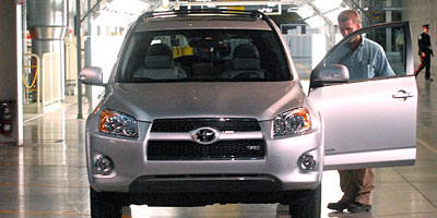 A Toyota employee opens the door of a new Toyota RAV4 after the car rolled off the production line at the grand opening of Toyota Motor Manufacturing Canada's "greenfield" plant in Woodstock, Ont., on Dec. 4, 2008.
