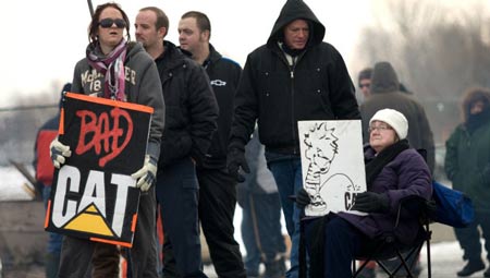 Anna Wittich, left, with sign, and Magdalena Schoenmakers, seated, join locked-out Electro-Motive workers on the picket line Friday in London, Ont. The Caterpillar plant's unionized workers were locked out of the factory Jan. 1, 2012.