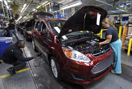 Workers make final tweaks to a C-Max Hybrid at the assembly plant in Wayne. Ford is on pace to sell a record number of electrified vehicles. (Todd McInturf / The Detroit News)