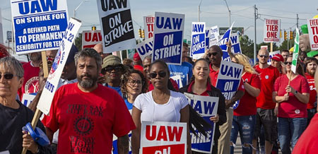 The new GM contract reflects the UAW picket sign "On Strike for a Defined Path to Permanent Seniority for Temps" (left), but it's a far cry from the grassroots sign, "Everyone Tier One" (right). Photo: Jim West/jimwestphoto.com
