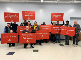 A group of people holding red signs with pro-worker messages